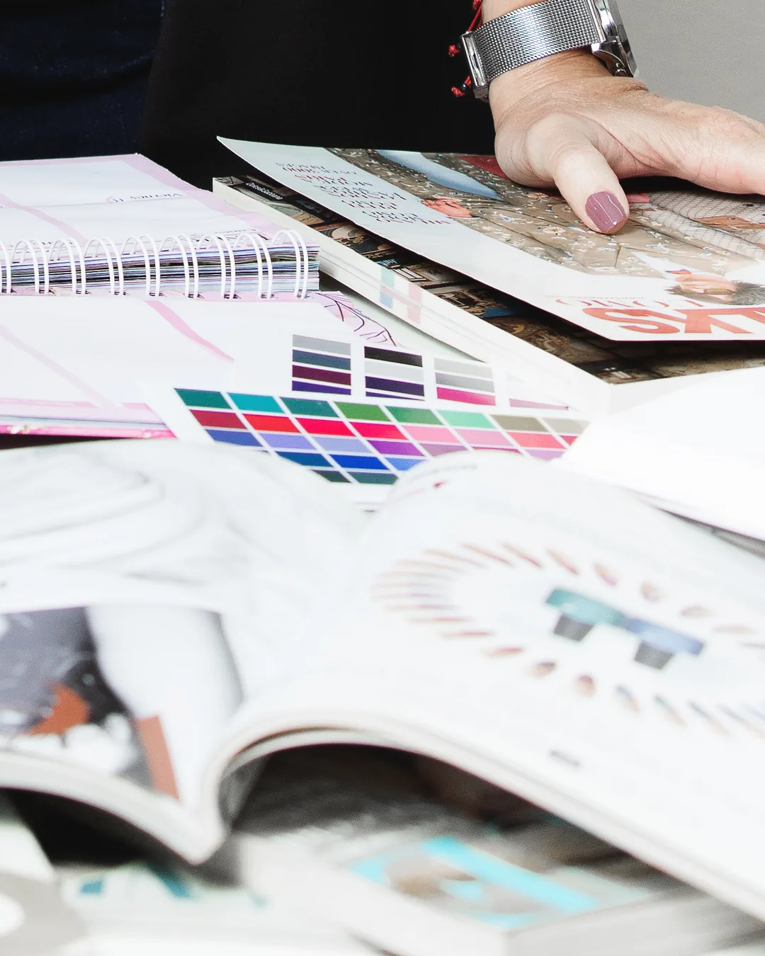 Cartas de color, paletas estacionales y revistas de moda sobre la mesa durante un análisis de colorimetría