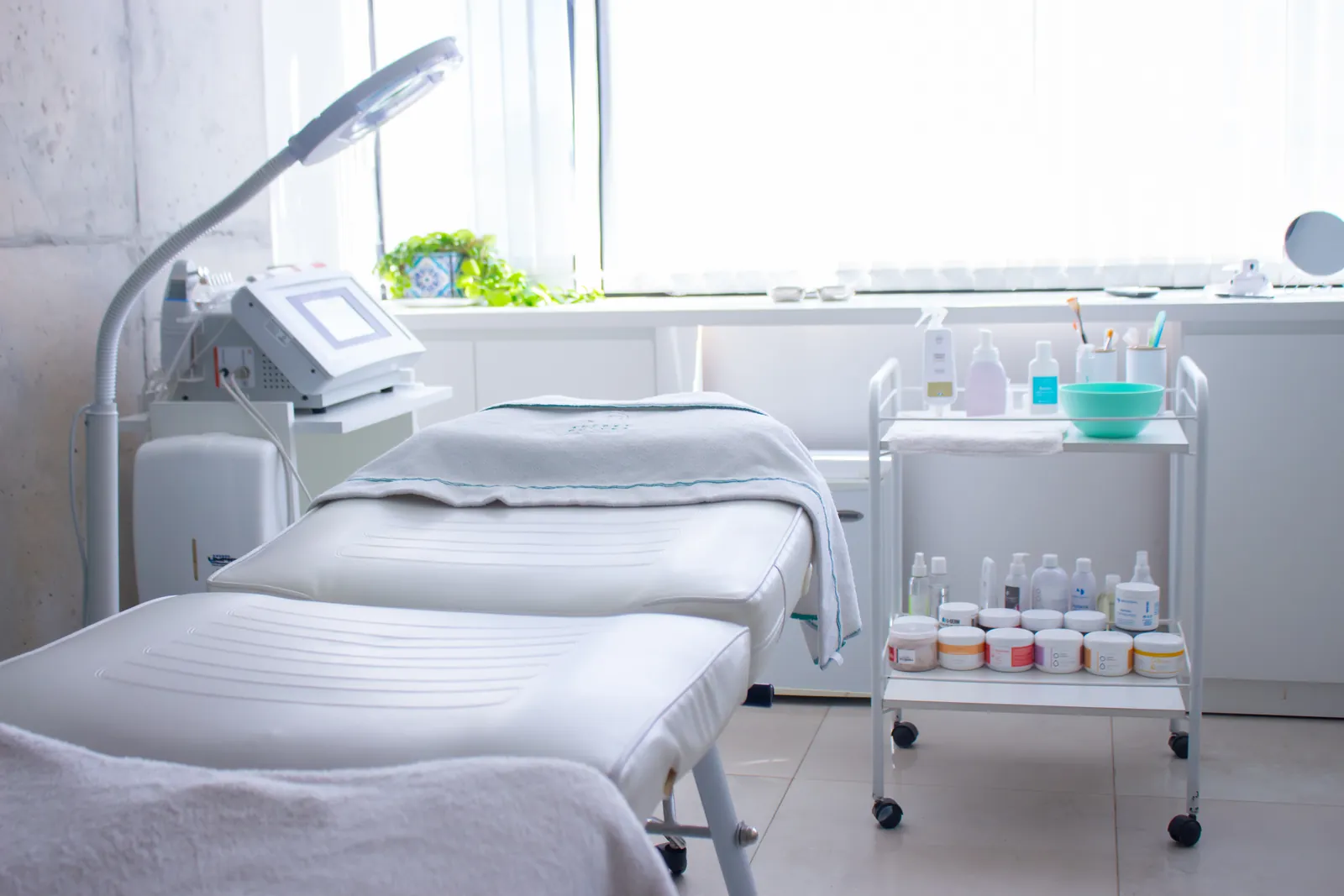 Gabinete facial con camillas, lupa de luz y carro de cosméticos