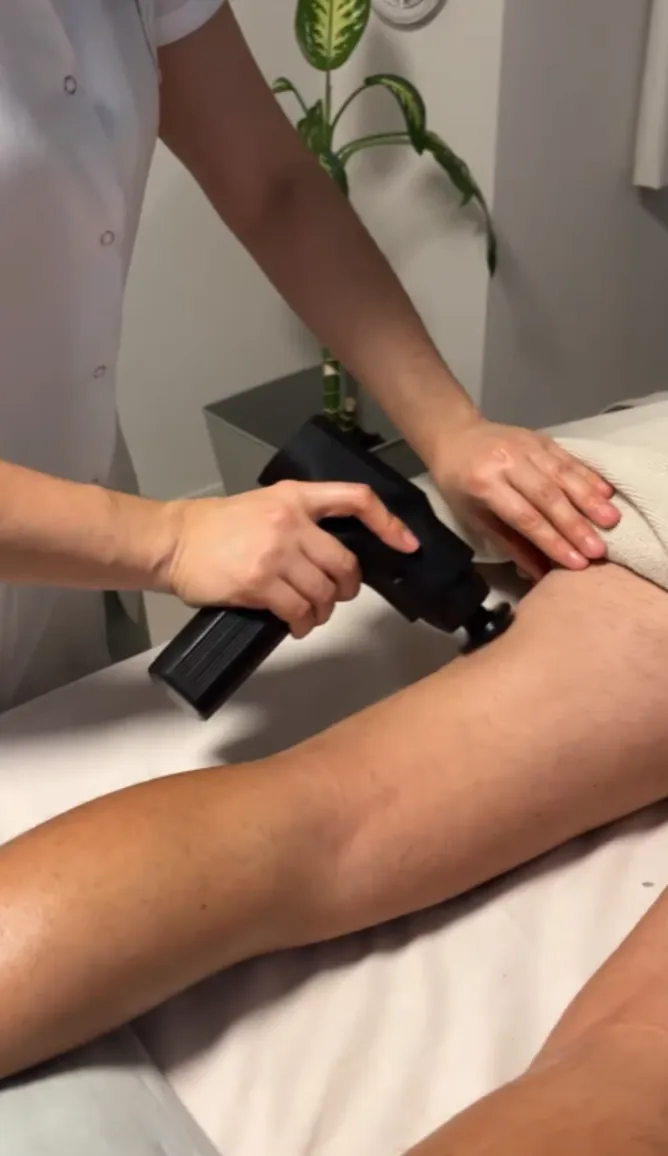 Masaje deportivo con pistola de percusión en la pierna